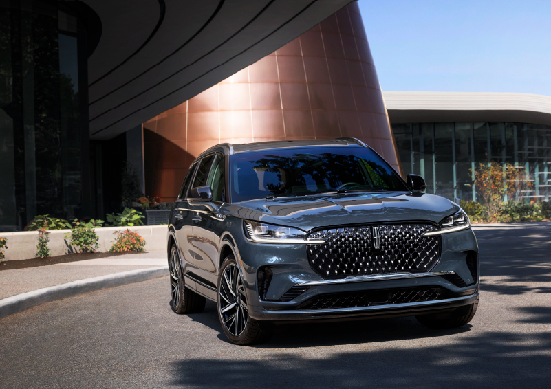 A gray 2025 Lincoln Aviator® SUV is parked outside a modern building with the sun shining. | Gary Yeomans Lincoln in Daytona Beach FL