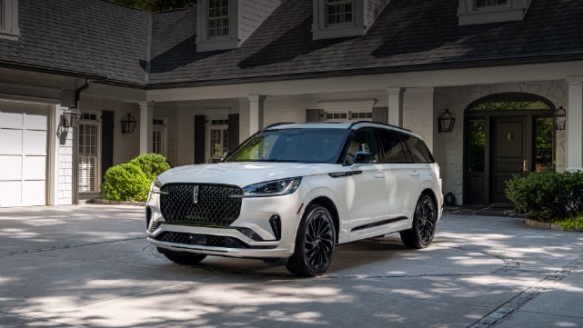 A white 2026 Lincoln Aviator® SUV is parked in the driveway of a luxury home. | Gary Yeomans Lincoln in Daytona Beach FL
