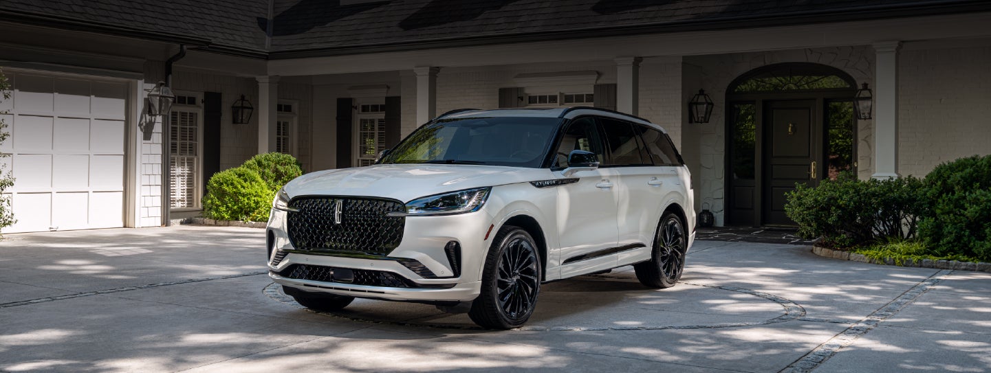A white 2026 Lincoln Aviator® SUV is parked in the driveway of a luxury home. | Gary Yeomans Lincoln in Daytona Beach FL