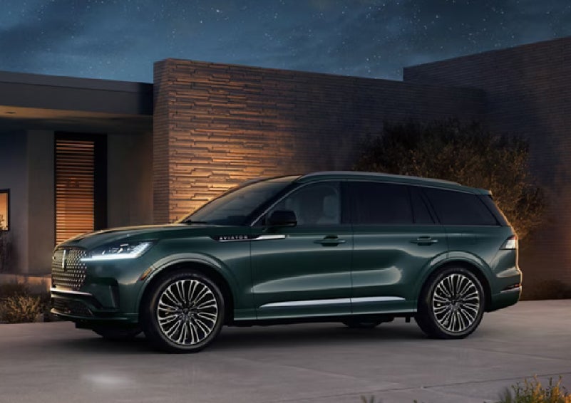 A green 2027 Lincoln Aviator® SUV is parked outside a contemporary home. | Gary Yeomans Lincoln in Daytona Beach FL