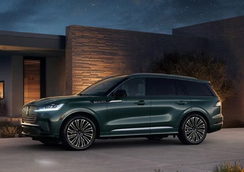 A green 2027 Lincoln Aviator® SUV is parked outside a contemporary home. | Gary Yeomans Lincoln in Daytona Beach FL