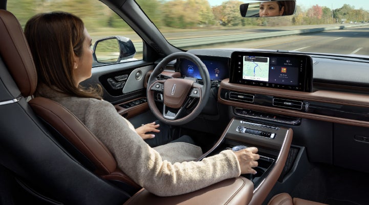 A 2027 Lincoln Aviator® SUV is being driven hands-free on a highway lined with trees. | Gary Yeomans Lincoln in Daytona Beach FL