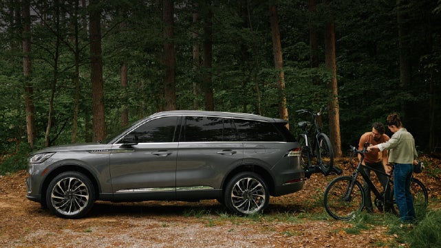 A father and son load e-bikes on a bike rack attached to a 2027 Lincoln Aviator® SUV. | Gary Yeomans Lincoln in Daytona Beach FL